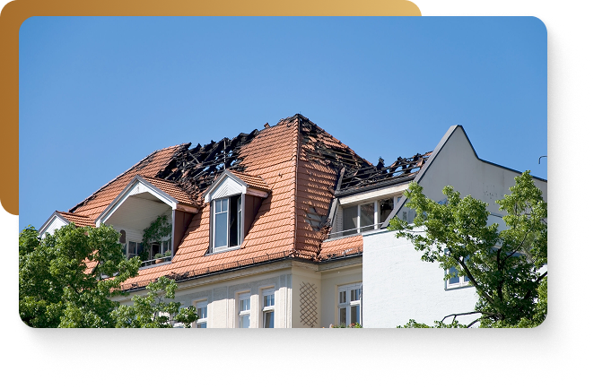 A white home with a severely damaged red roof caused by significant fire damage