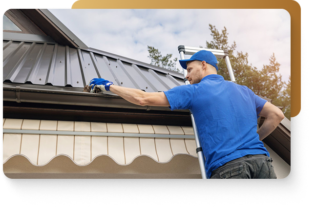 A man in blue shirt, blue hat, and blue gloves standing on a ladder cleaning a gutter after installation