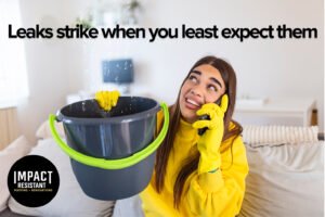 Blogs 3 A woman wearing a yellow raincoat and wearing yellow gloves holds up a blue bucket with one hand to catch dripping water from the ceiling, while holding a phone to hear head with another hand in order to call for help